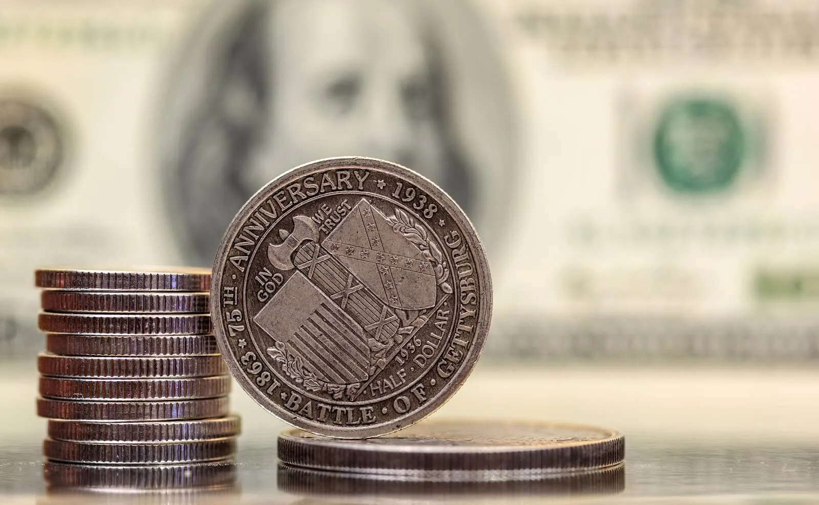 Close-up image of a 1938 commemorative half dollar coin marking the 75th anniversary of the Battle of Gettysburg, with stacked coins nearby